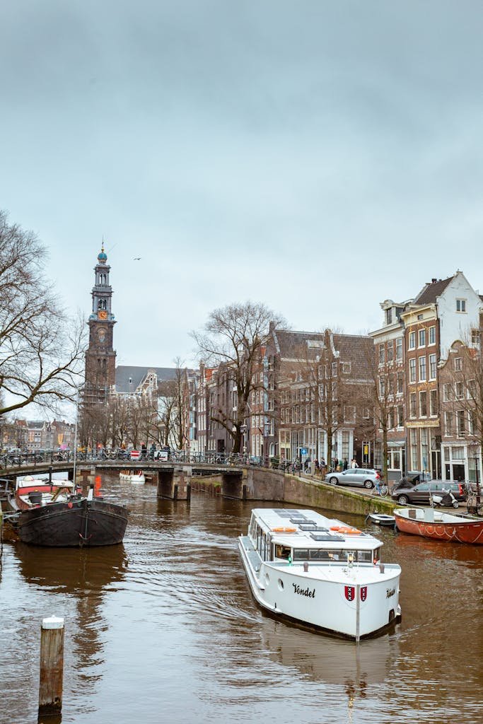 Charming view of an Amsterdam canal featuring historic buildings and boats on an overcast day.