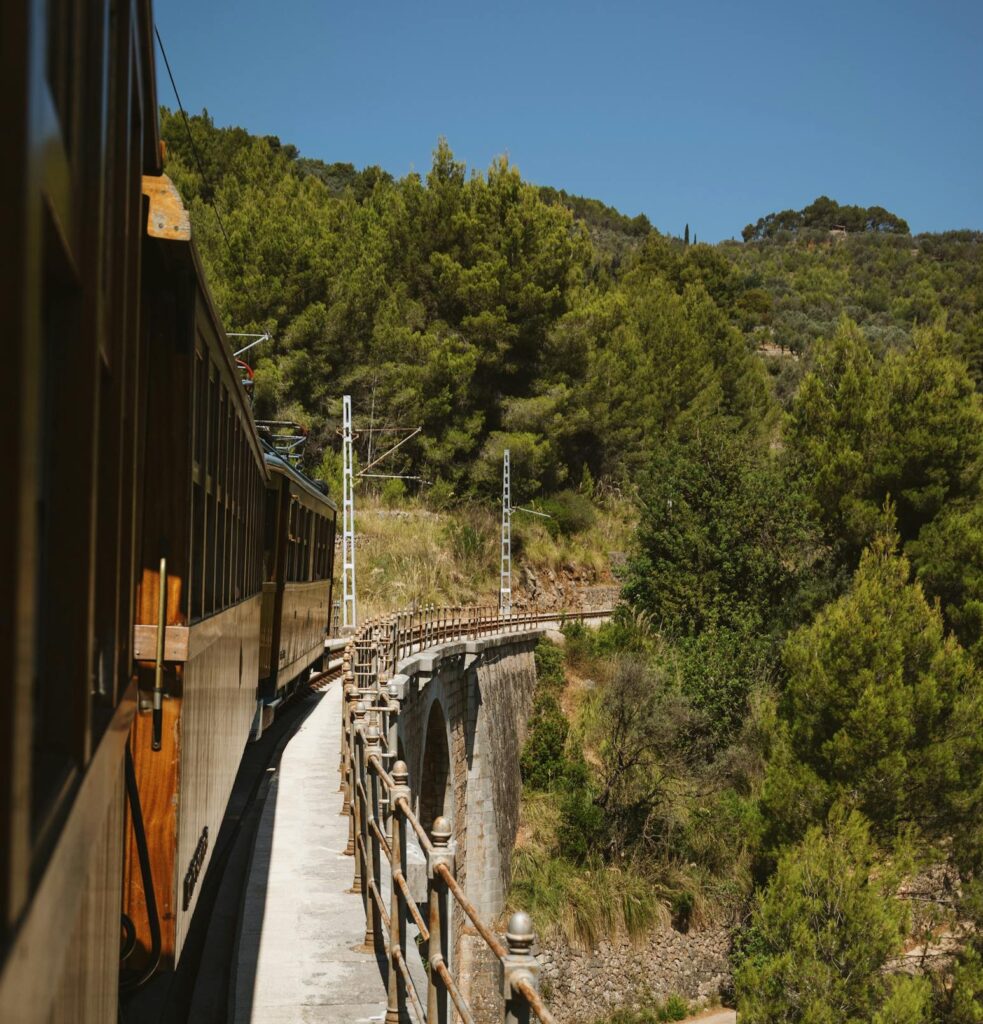 Vintage train traverses scenic mountains in Mallorca, showcasing stunning Mediterranean views.