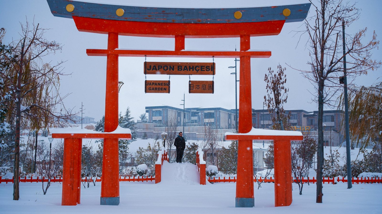 A snowy winter day at a Japanese garden with a vibrant red Torii gate.
